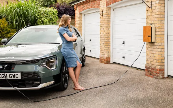 Wall-mounted home EV charger on a garage wall charging an electric car in the driveway