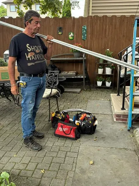 Michael Livia, owner of Premier Electrical Contractors, carrying metal conduit on a Staten Island job site