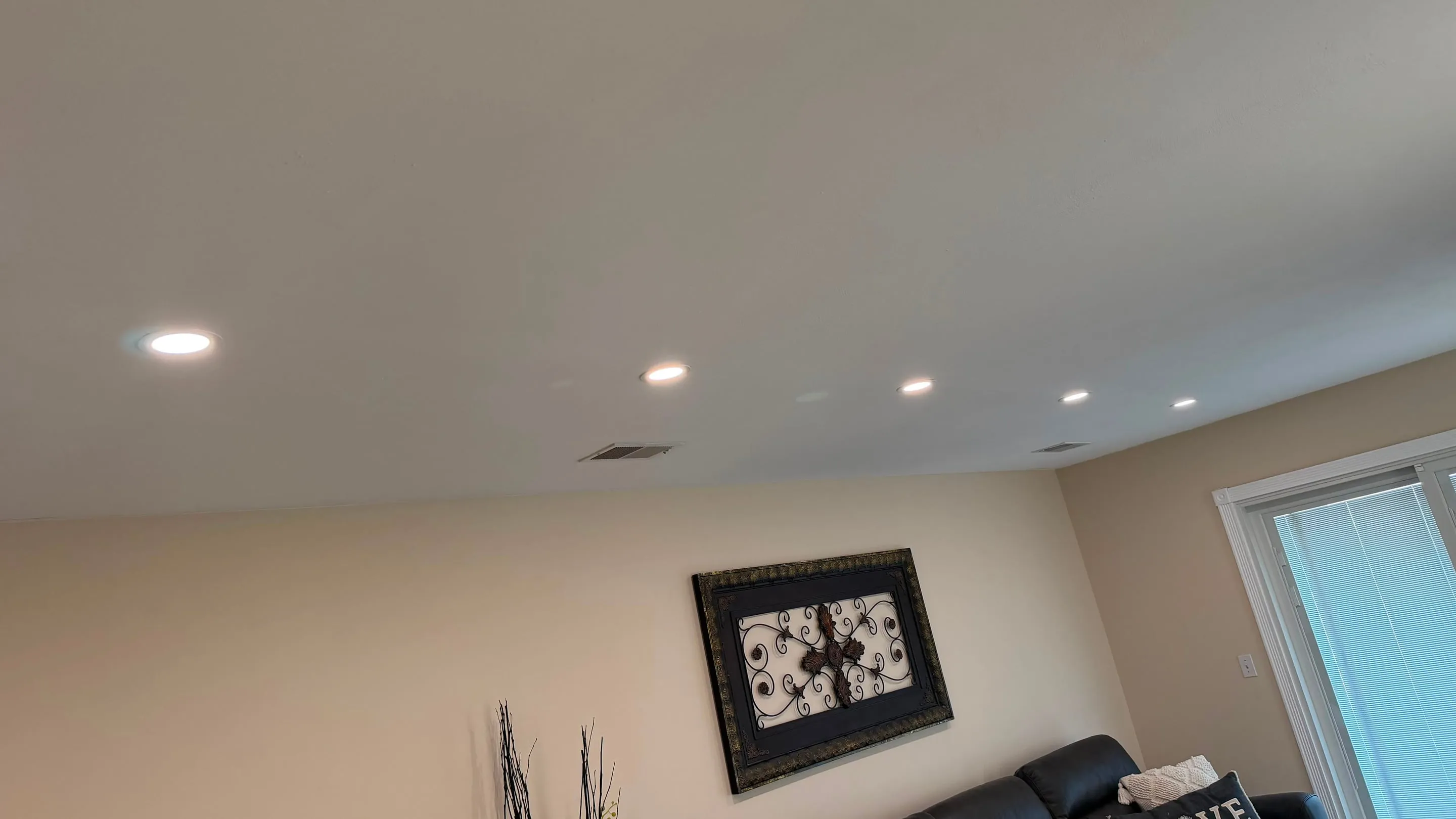 Row of lit recessed can lights installed across a residential living room ceiling